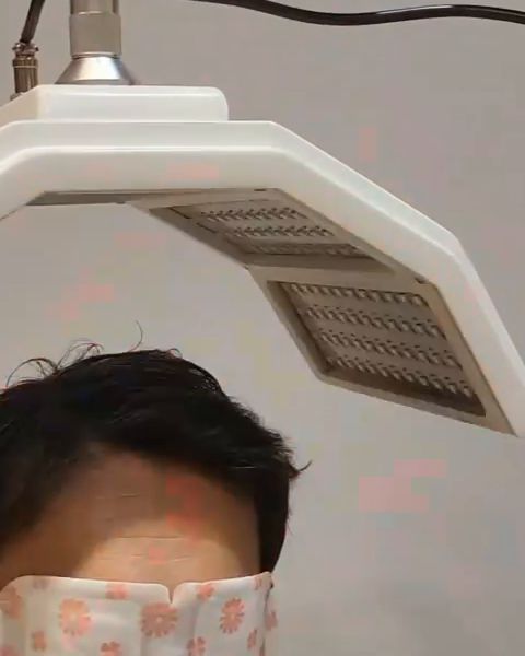 Guest with an eye-steam mask resting under the LED light panel
